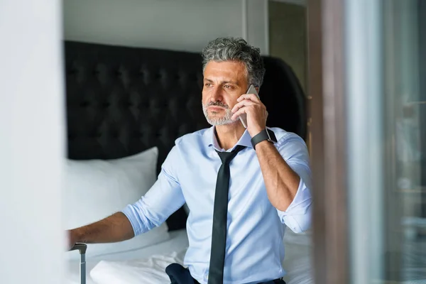 Mature businessman with smartphone in a hotel room. — Stock Photo, Image