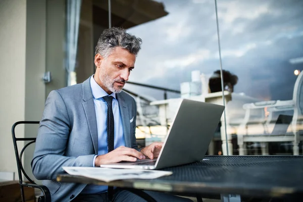 Rijpe zakenman met laptop op een terras van het hotel. — Stockfoto