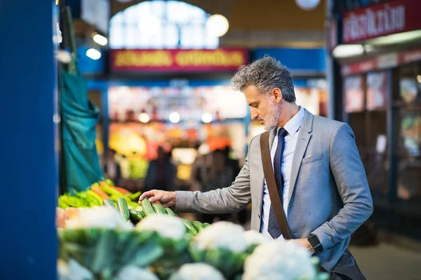 Homme d'affaires mature achetant des légumes dans une ville . — Photo