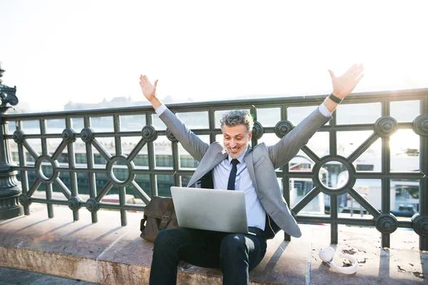 Homme d'affaires mature avec un ordinateur portable dans une ville . — Photo