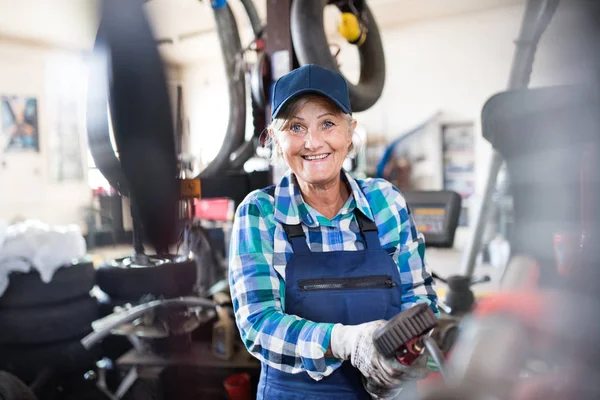 Старшая женщина-механик ремонтирует машину в гараже . — стоковое фото