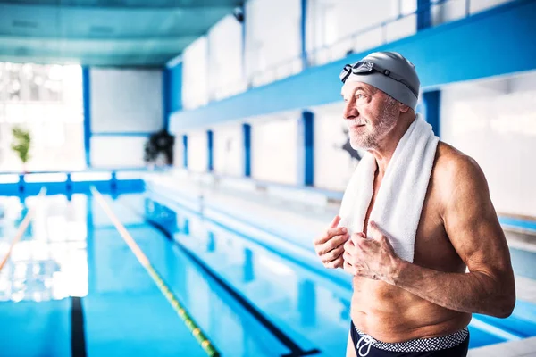 Senior man die door het overdekte zwembad. — Stockfoto