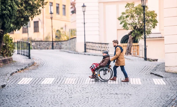 Père aîné en fauteuil roulant et jeune fils en promenade . — Photo