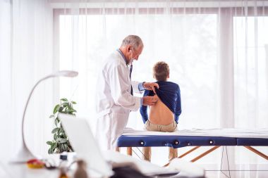 Kıdemli doktor ofisinde küçük bir çocuk incelenmesi.