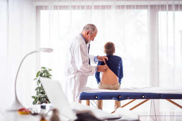 Senior medico visita un piccolo ragazzo nel suo ufficio . — Foto Stock