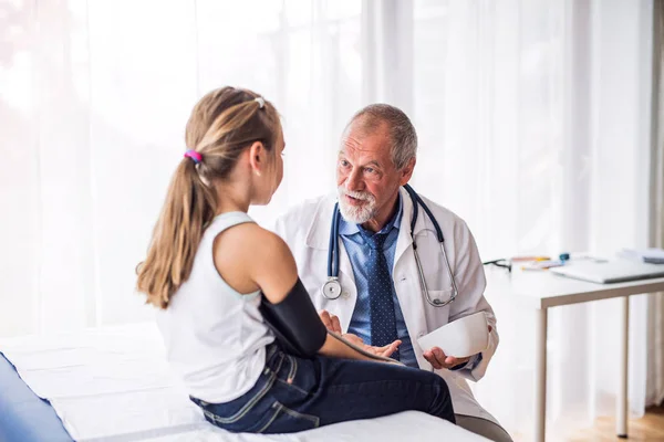 Senior doctor checking a small girl in his office. — Stock Photo, Image