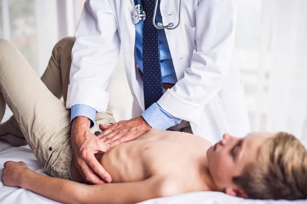 Médico mayor examinando a un niño pequeño en su consultorio . — Foto de Stock