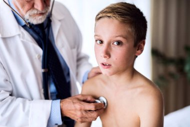 Kıdemli doktor ofisinde küçük bir çocuk incelenmesi.