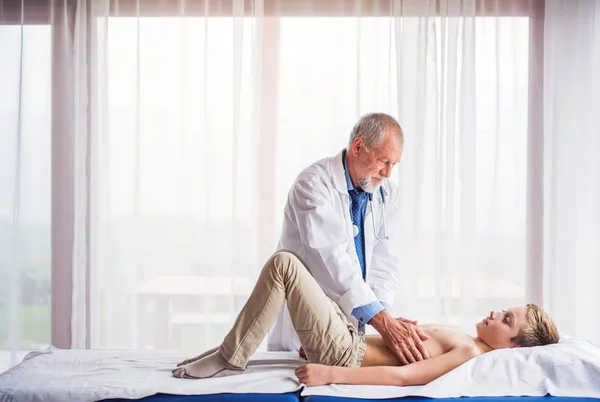 Ledande läkare undersöker en liten pojke i hans kontor. — Stockfoto