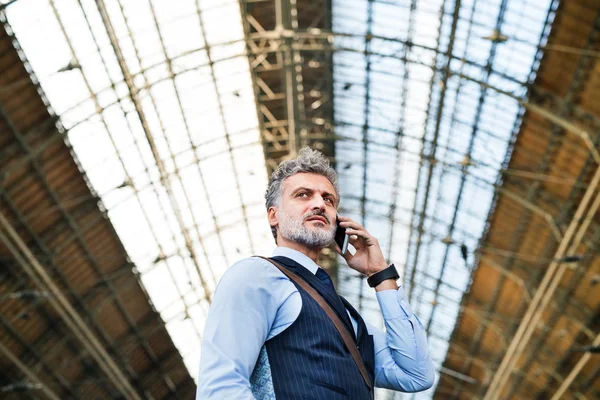 Uomo d'affari maturo con smartphone su una stazione ferroviaria . — Foto Stock