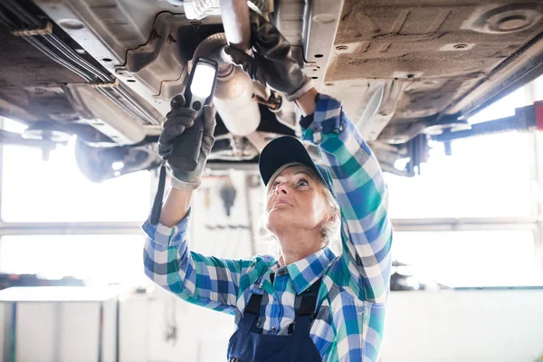 Retrato de uma mecânica feminina sênior em uma garagem . — Fotografia de Stock