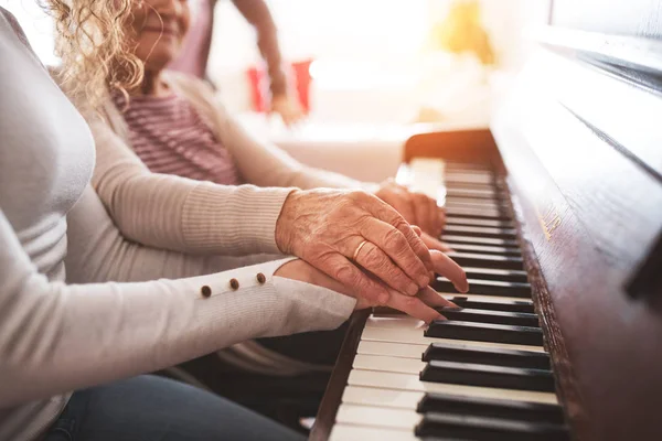 Une fille avec grand-mère jouant du piano . — Photo