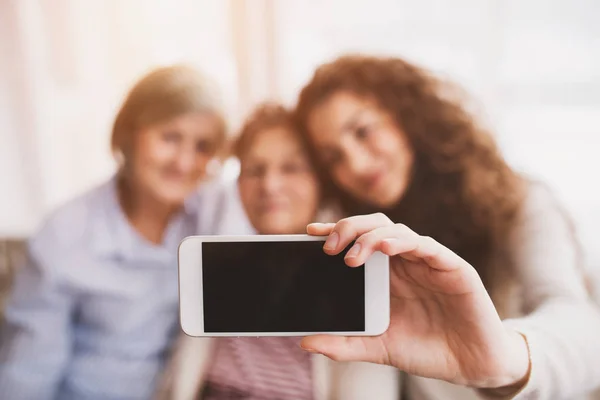 Bir genç kız, annesi ve büyükannesi ile evde smartphone. — Stok fotoğraf