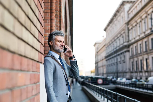 Uomo d'affari maturo con smartphone in una città . — Foto Stock