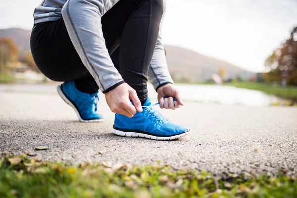 Onherkenbaar jonge runner koppelverkoop schoenveters. — Stockfoto