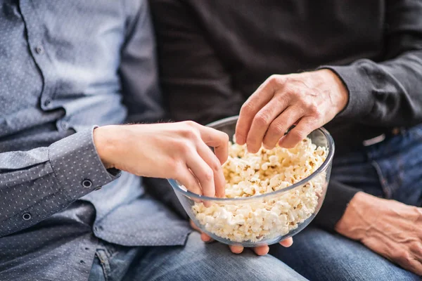 息子と家でポップコーンを食べる彼の上級の父. — ストック写真