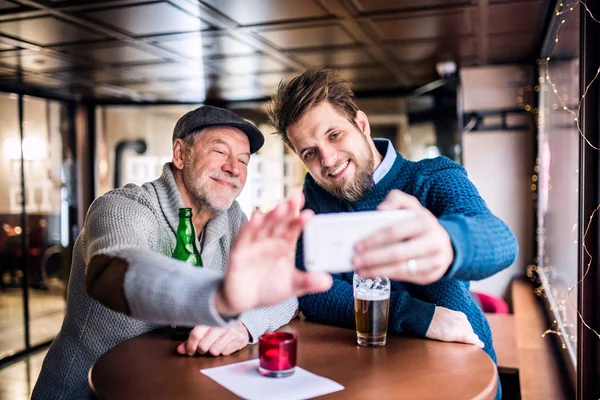 Vezető apa és fia, egy pub-ban smartphone. — Stock Fotó