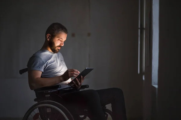 Adam tekerlekli sandalyeye mahkum tablet ile çalışma. — Stok fotoğraf