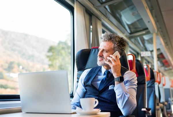 Homme d'affaires mature avec smartphone voyageant en train . — Photo