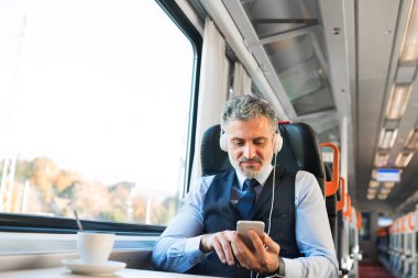Tren ile seyahat eden smartphone ile olgun iş adamı.