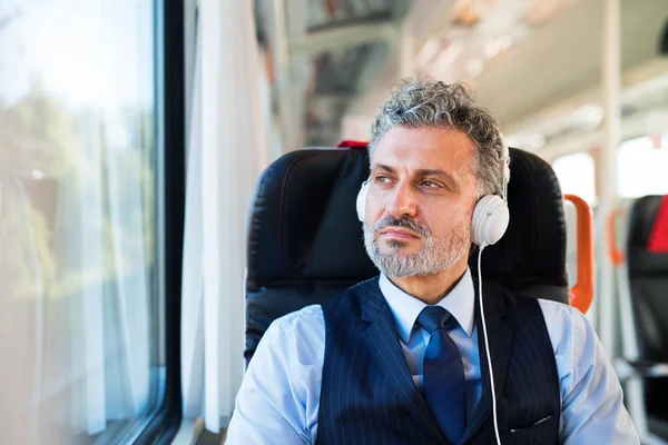 Dojrzałe biznesmen z słuchawki podróży pociągiem. — Zdjęcie stockowe