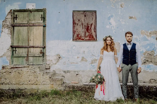 Bela noiva e noivo na frente da velha casa miserável . — Fotografia de Stock