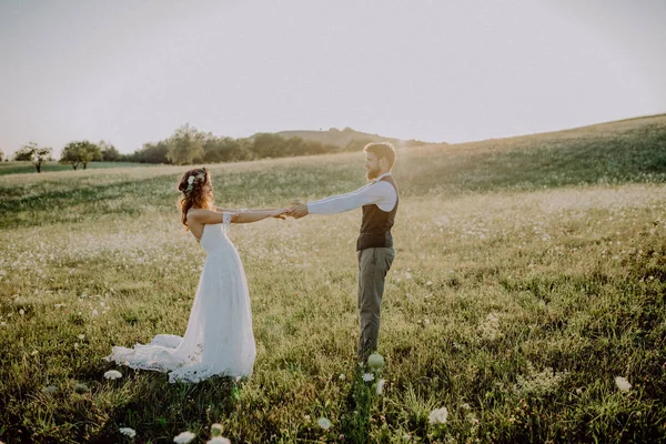Mooie bruid en bruidegom bij zonsondergang in de groene natuur. — Stockfoto