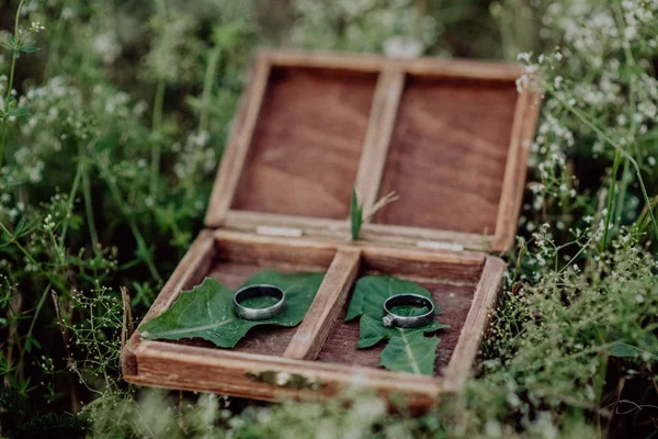 Anéis de casamento em uma caixa de madeira na grama . — Fotografia de Stock