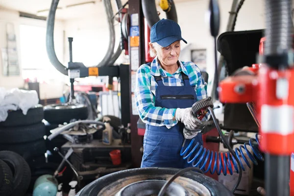 Senior női szerelő, javítás egy autó a garázsban. — Stock Fotó
