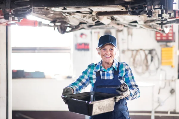 Portret van een senior vrouwelijke monteur in een garage. — Stockfoto