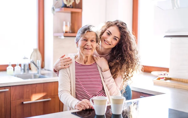 Een tienermeisje met grootmoeder thuis. — Stockfoto