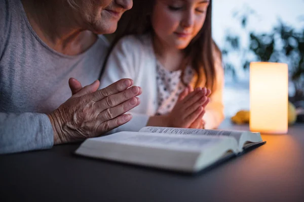 A small girl and grandmother praying at home. — Stock Photo, Image