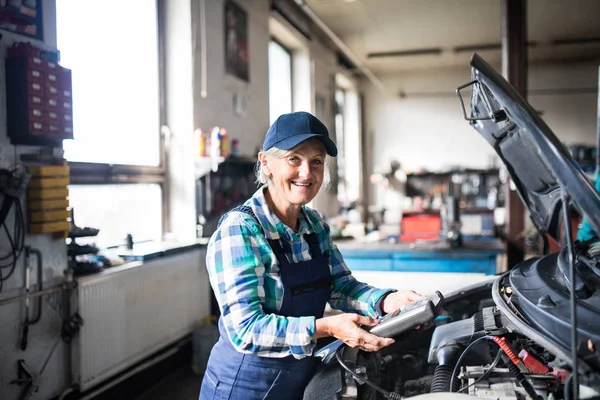 Mecánica femenina mayor reparando un coche en un garaje . — Foto de Stock