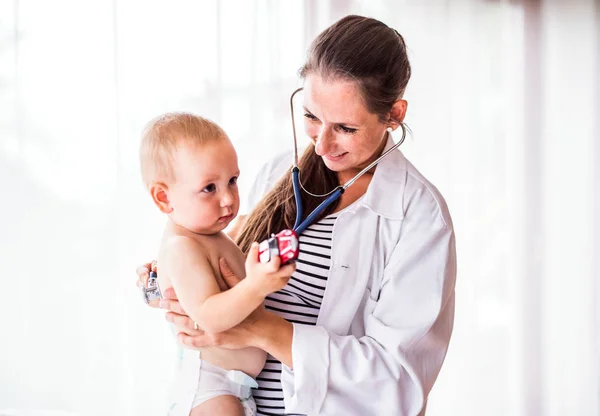 Médico joven examinando a un niño en un consultorio . — Foto de Stock