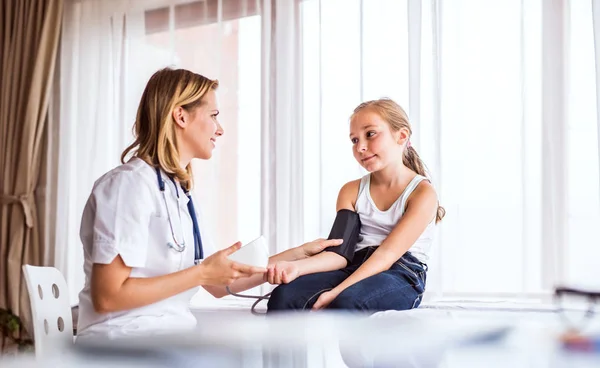 Junge Ärztin überprüft ein kleines Mädchen in ihrem Büro. — Stockfoto