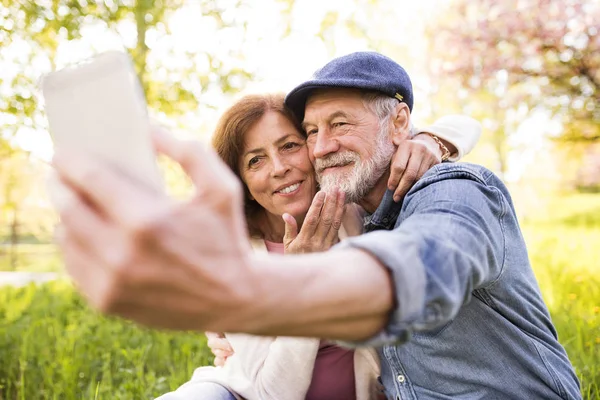 Senior couple with smartphone outside in spring nature. — Stock Photo, Image