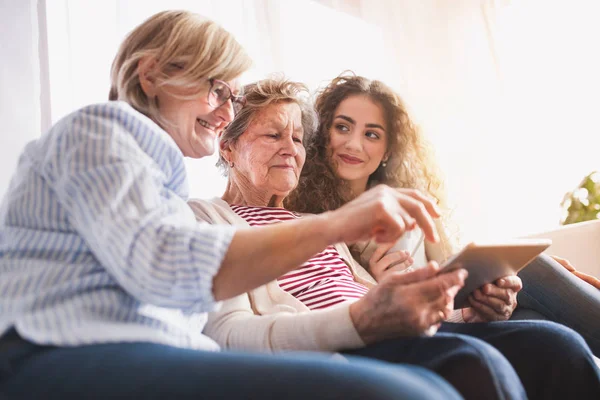 Een tienermeisje, moeder en grootmoeder met Tablet PC thuis. — Stockfoto