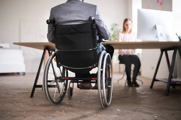 Два бизнесмена с инвалидной коляской в офисе . — стоковое фото