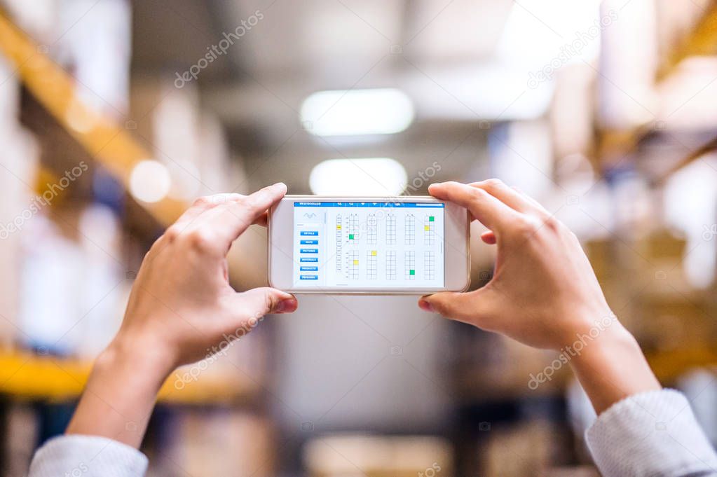 Woman warehouse worker with smartphone.