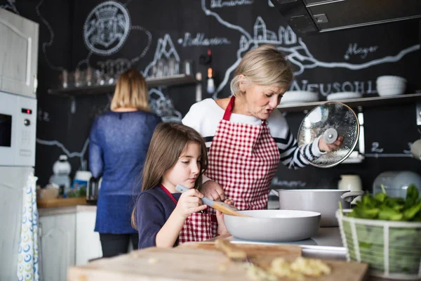 A small girl with mother and grandmother at home. — Stock Photo, Image