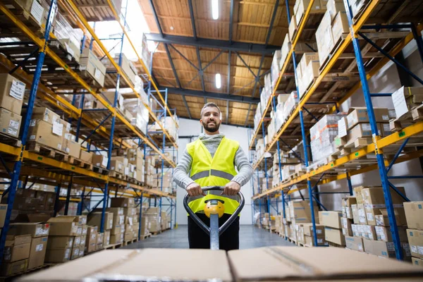 Mannelijke magazijnmedewerker trekken een pallettruck. — Stockfoto