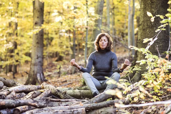 Старшая женщина медитирует в осеннем лесу . — стоковое фото