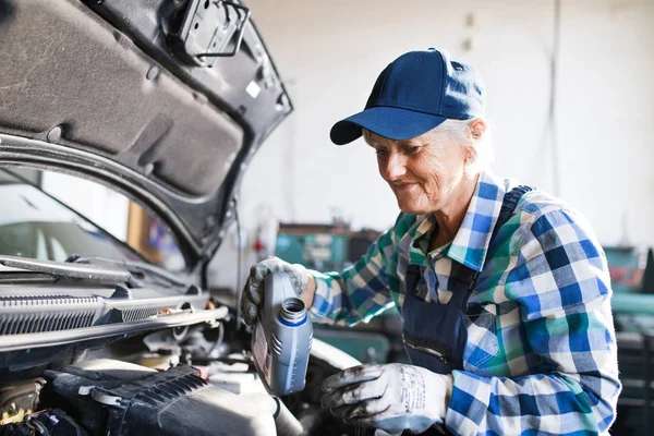 Mecânico feminino sênior reparando um carro em uma garagem . — Fotografia de Stock