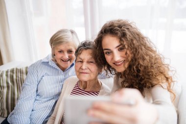 Bir genç kız, annesi ve büyükannesi ile evde smartphone.