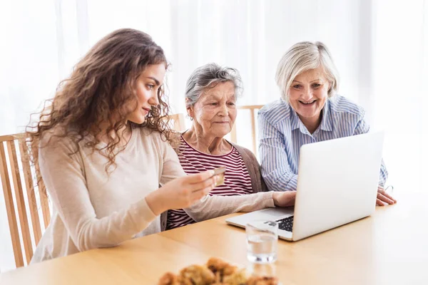 En tonårig flicka, mor och mormor med laptop hemma. — Stockfoto