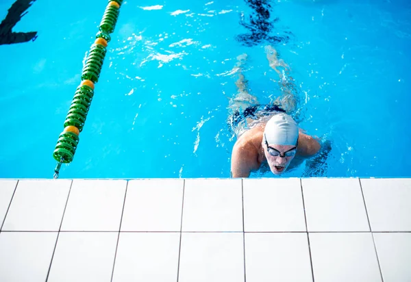 Senior man swimming in an indoor swimming pool. — Stock Photo, Image