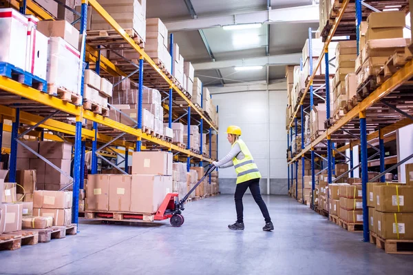 Vrouw magazijnmedewerker met hand heftruck. — Stockfoto