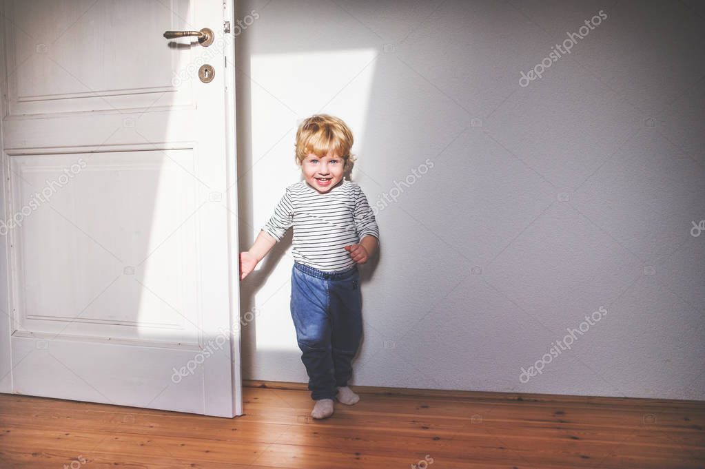 Cute toddler boy standing in a bedroom.