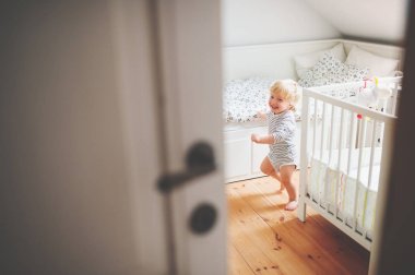 Bir yatak odasında çalışan şirin yürümeye başlayan çocuk.