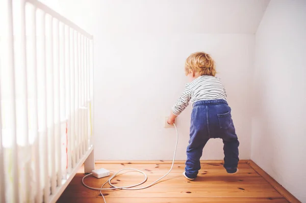 Μικρό παιδί αγόρι σε μια επικίνδυνη κατάσταση στο σπίτι. — Φωτογραφία Αρχείου
